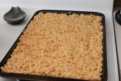A cookie sheet full of mixed melted marshmallow, butter and rice crispies.