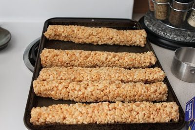 five rolled rice crispies in a cookie sheet.