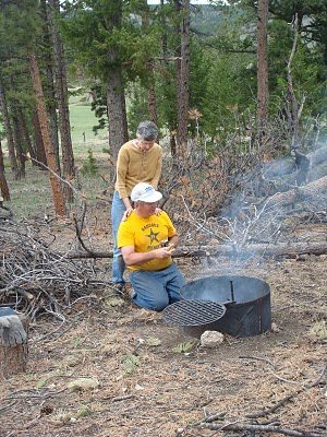 a man and woman standing around a fire pit.
