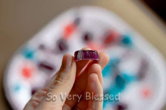 A hand holding a violet candy.