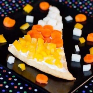 Veggie pizza slices shaped like candy corn, topped with colorful fresh vegetables