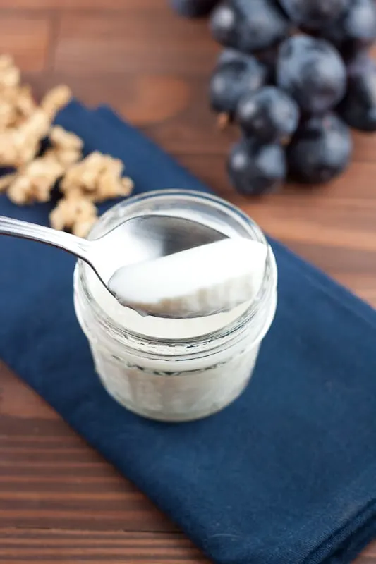 spoonful of yogurt with grapes and granola in the background