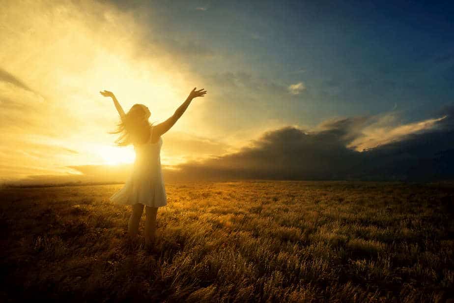 woman worshiping with hands raised in a field