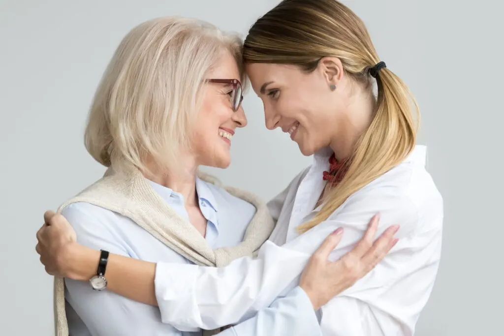 two women smiling, hugging, and looking at each other