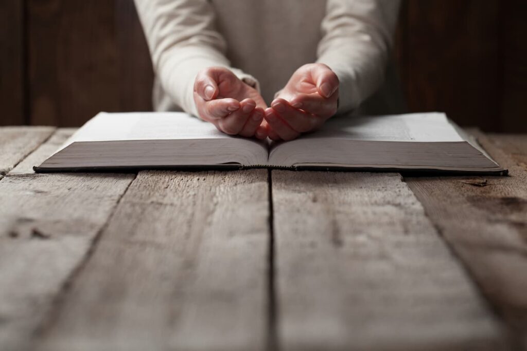 woman with open hands on her Bible in prayer