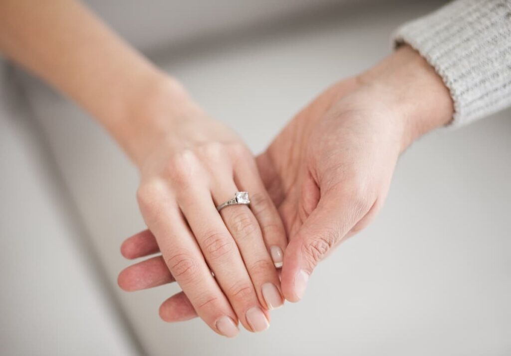 Bible Verses On Marriage - husband holding his wife's hand, showing wife's wedding ring