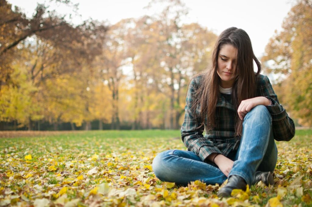 Prayers for grieving loss of a loved one - grieving women sitting on the ground looking down with sadness