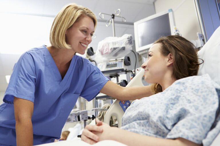 Prayers Before Surgery - female nurse comforting woman patient in a hospital bed with a hand on her shoulder and a smile