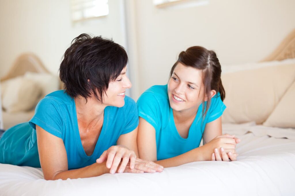 Prayers For Parents Of Teenagers - mother laying on bed looking at her teenage daughter