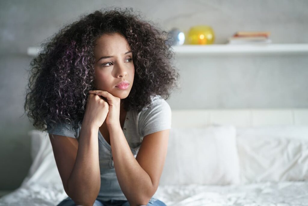Prayers For A Broken Heart - sad woman sitting on bed staring to the right