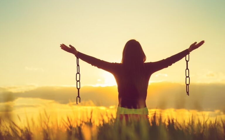Prayers For Forgiveness From Sins - woman standing in a field holding her arms out, showing broken chains hanging down from each arm