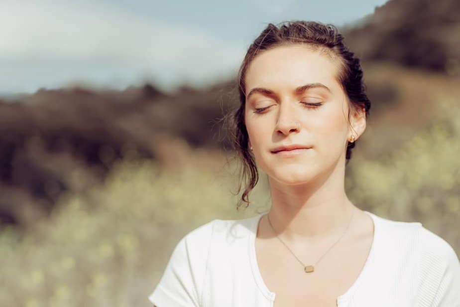 Woman outdoors eyes closed looking pensive