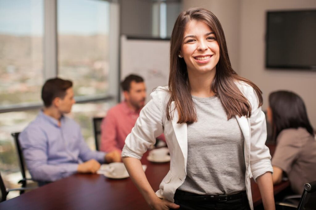 Business woman smiling in front of colleagues in a conference room