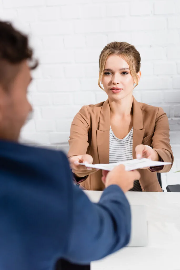 Young woman handing an interviewer her resume