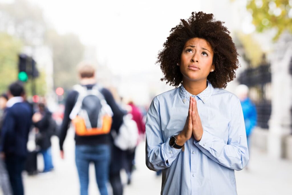 Young black woman praying on blurred background