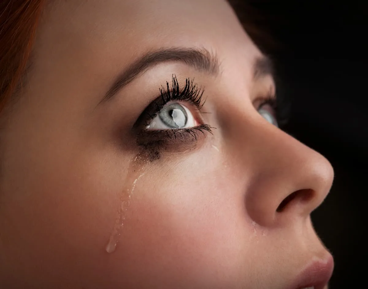 woman with tear rolling down her cheek looking up