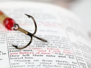 Fishing Hook on top of a bible showing Bible Verse about discipleship with words in red saying I will make you fishers of men.