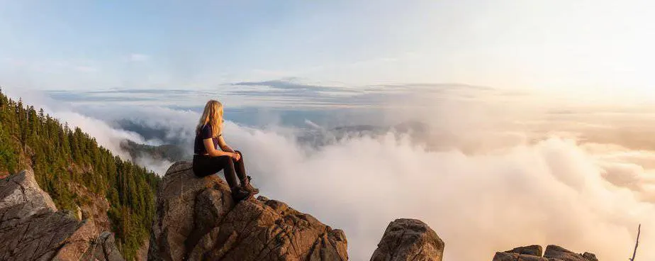 Adventurous Female Hiker on top of a mountain covered in clouds for 32 Bible verses about adventure