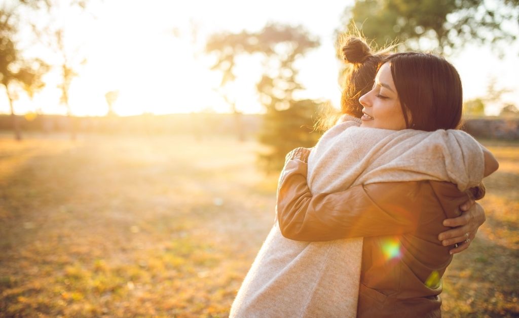 Two women share a warm hug in the evening sun, reflecting the gift of women’s emotions in small churches.