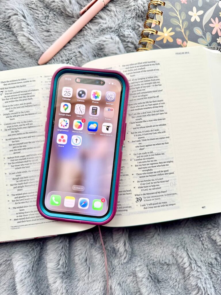 Phone sitting on top of a Bible, notebook, and pen