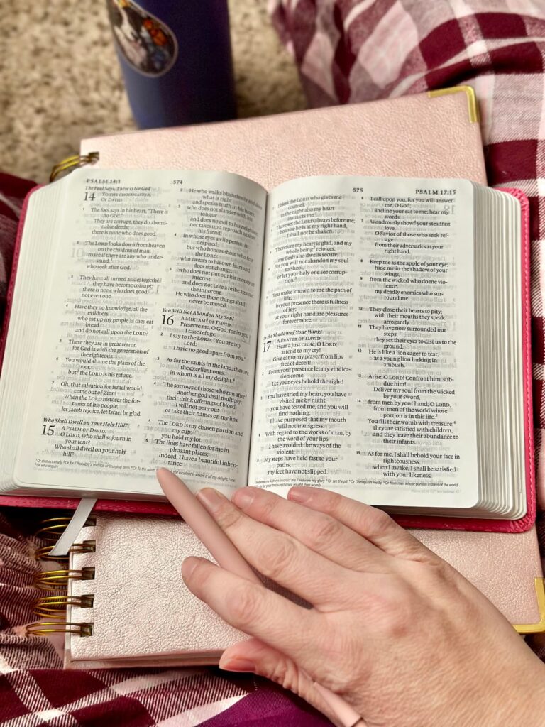 Woman's hand resting on her journal and Bible with a pen