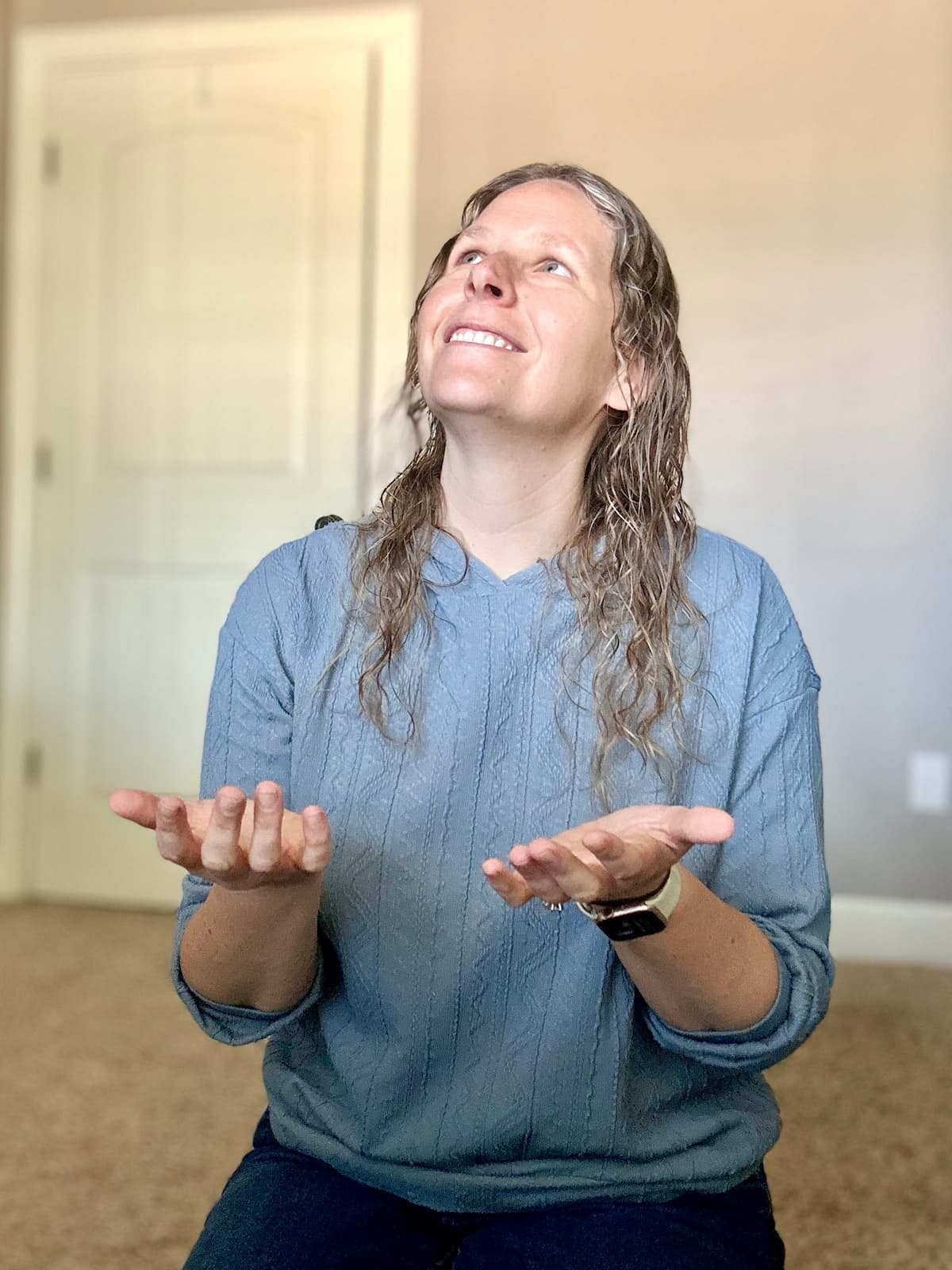 Woman kneeling holding her hands out in front of her smiling and looking up towards God