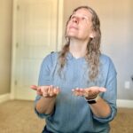 Woman kneeling on the floor with open hands looking up in prayer