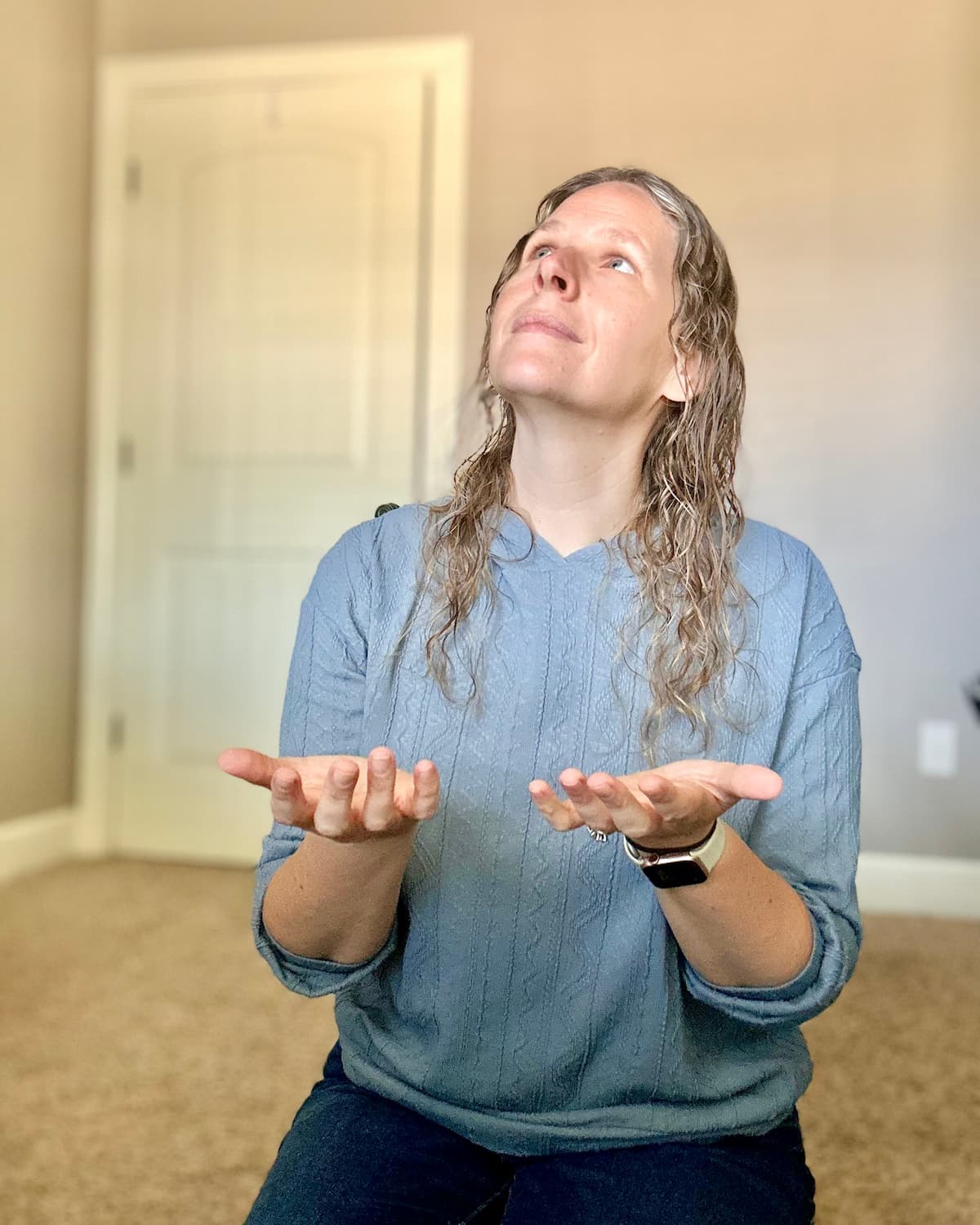 Woman kneeling on the floor with open hands looking up in prayer